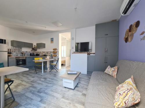 un salon avec un canapé et une cuisine dans l'établissement Pescad Home Maison 3 étoiles plein centre de Valras à 130m de la plage, à Valras-Plage