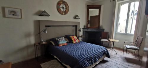 a bedroom with a bed and a clock on the wall at Chambres d'Hôtes Le Mimosa in Saint-Saturnin-de-Lucian