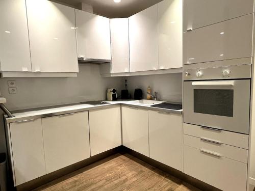 Il comprend une cuisine blanche avec des placards blancs et du parquet. dans l'établissement GoodGuest Paris Montorgueil Bail Mobilité, à Paris