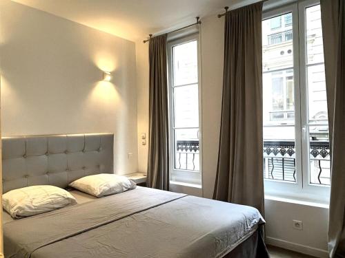 une chambre avec un lit et deux fenêtres dans l'établissement GoodGuest Paris Montorgueil Bail Mobilité, à Paris