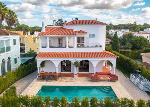 a villa with a swimming pool in front of a house at Luxurious Villa - Pool, Hot Tub, Cinema and Golf in Vilamoura