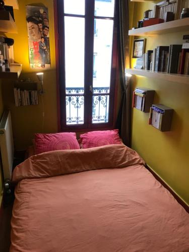 un lit dans une chambre avec une fenêtre dans l'établissement Charming flat in Belleville, à Paris