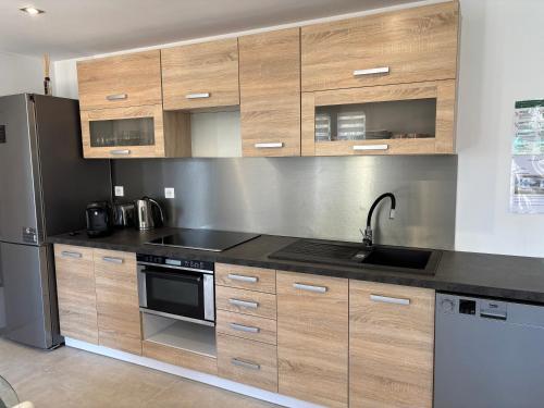 a kitchen with wooden cabinets and a stainless steel refrigerator at Appartement avec jacuzzi in Porto-Vecchio