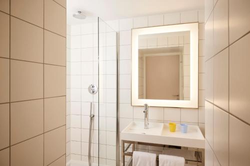 a white bathroom with a sink and a mirror at Mama Shelter Paris East in Paris