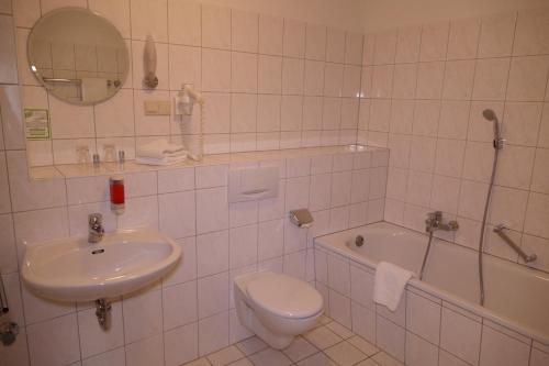 a bathroom with a sink and a toilet and a tub at Hotel Am Dom in Greifswald