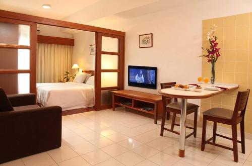 a hotel room with a bed and a table and a television at Richone Maluri Private Hotel in Kuala Lumpur