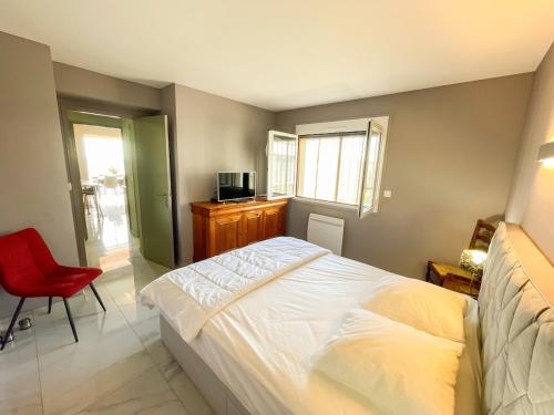 une chambre avec un lit blanc et une chaise rouge dans l'établissement Spacieux T2 au bord de l'eau, vue panoramique, à Six-Fours-les-Plages