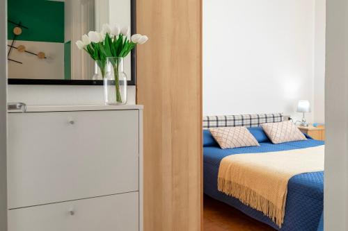 a bedroom with a bed and a vase with white flowers at Appartamento Cerri in Badesi