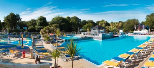 - une grande piscine avec des chaises et des parasols dans un complexe dans l'établissement Mobilhome sur Pont-Aven, à Pont-Aven