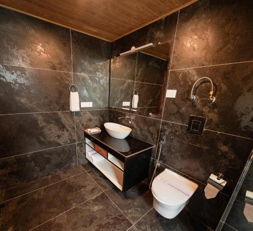 a bathroom with a toilet and a sink at Nazaara - A Luxe Retreat in Manāli