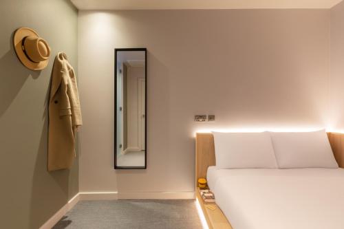 a bedroom with a bed and a mirror on the wall at Zedwell Hotel Greenwich in London