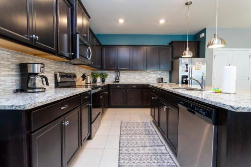 una cucina con mobili in legno scuro e ripiani in marmo di Encantada Rose - a 4 bed townhouse near Disney a Kissimmee