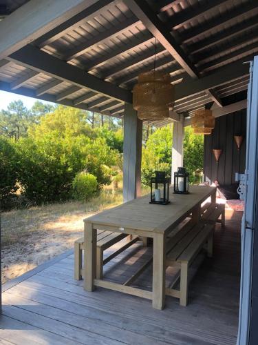 une table de pique-nique en bois sur un porche avec un toit dans l'établissement Pura Vida, à Lège-Cap-Ferret