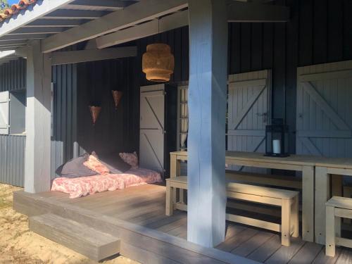 - une terrasse couverte d'une maison avec 2 lits et des bancs dans l'établissement Pura Vida, à Lège-Cap-Ferret