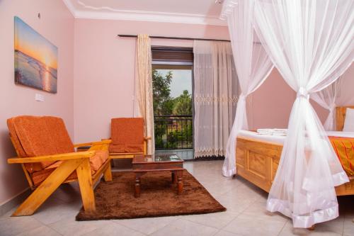 a bedroom with a bed and a chair and a window at SILVER OAKS HOTEL Boma in Fort Portal