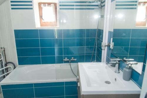 a blue and white bathroom with a sink and a tub at Gite l'anemone in Saint-Pierre-des-Tripiers
