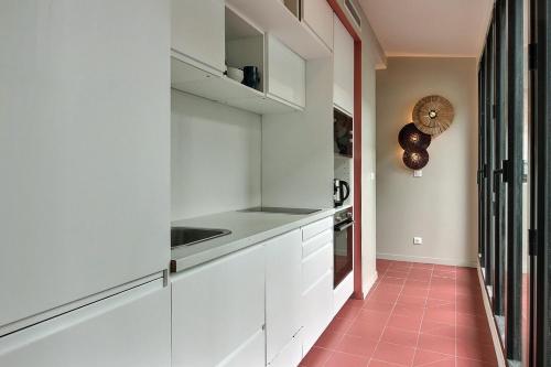 d'une cuisine avec des placards blancs et du carrelage rose. dans l'établissement PARISIAN HOME l MARAIS, à Paris