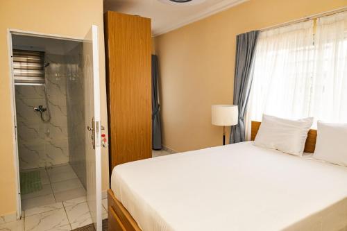 a bedroom with a white bed and a shower at Everyone deserves to rest from their labor in Kweman