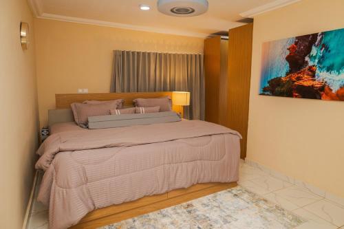 a bedroom with a bed and a painting on the wall at Everyone deserves to rest from their labor in Kweman