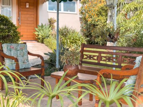 two wooden benches sitting on a patio with plants at Pousada Quinta dos Colibris in São Bento do Sapucaí