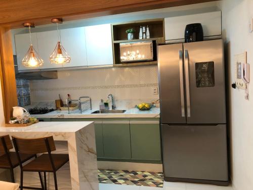 a kitchen with a stainless steel refrigerator and a table at Vista mar sol&mar in Vila Velha