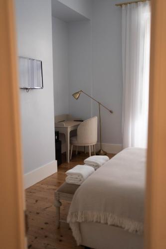 a bedroom with a bed and a desk with a lamp at Palácio do Visconde - The Coffee Experience in Lisbon