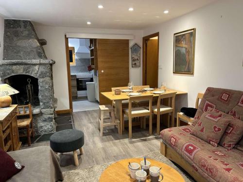 - un salon avec un canapé, une table et une cheminée dans l'établissement Appartement chaleureux avec terrasse, à 250m des pistes - Méribel, animaux acceptés - FR-1-180-344, à Méribel