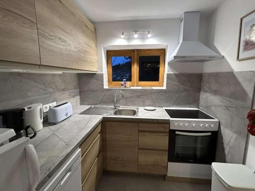 une cuisine avec un évier et une cuisinière four supérieur dans l'établissement Appartement chaleureux avec terrasse, à 250m des pistes - Méribel, animaux acceptés - FR-1-180-344, à Méribel