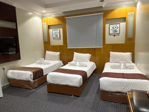a hotel room with two beds and a flat screen tv at فندق المغاربي للشقق الفندقية in Al Madinah