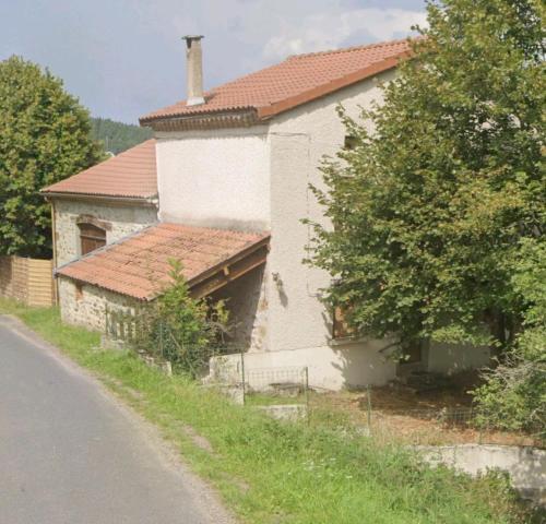 une vieille maison blanche sur le côté d'une route dans l'établissement Maison de campagne 60m2, à Tailhac