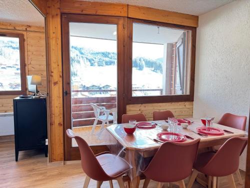 une salle à manger avec une table, des chaises et des fenêtres dans l'établissement Appartement aux Gets avec vue et animaux acceptés - FR-1-623-143, aux Gets