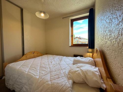 une chambre avec un lit blanc avec une fenêtre dans l'établissement Appartement aux Gets avec vue et animaux acceptés - FR-1-623-143, aux Gets