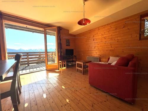 un salon avec un canapé rouge et un balcon dans l'établissement F4 bas de chalet avec terrasse et parking - Les Angles - FR-1-295-143, aux Angles