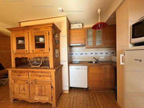 une cuisine avec des armoires en bois et un réfrigérateur blanc dans l'établissement F4 bas de chalet avec terrasse et parking - Les Angles - FR-1-295-143, aux Angles