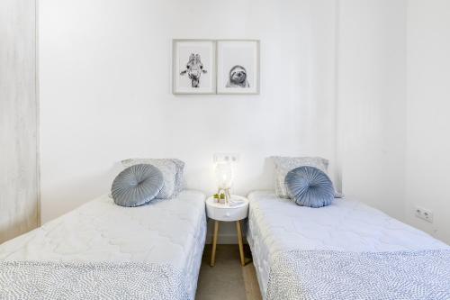 - 2 lits dans une chambre blanche avec des oreillers bleus dans l'établissement Gran Reserva Mimoses Premium, à Empuriabrava