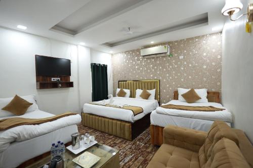 a hotel room with two beds and a couch at The Tulsi Garden - Ashram vihar vrindavan in Vrindāvan