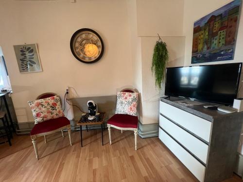 a living room with two chairs and a tv at Vivez un conte de fée dans la pièce ronde d'une tour médiévale in Porrentruy