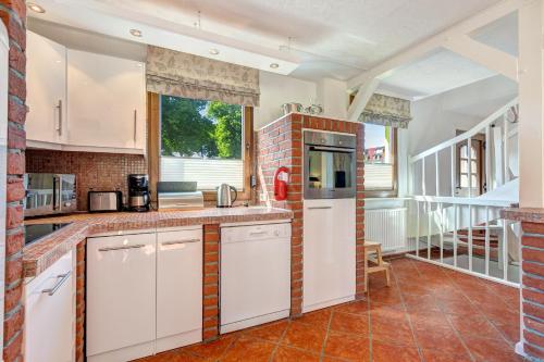 a kitchen with white cabinets and a brick wall at Haus Kieferngrund in Ahlbeck