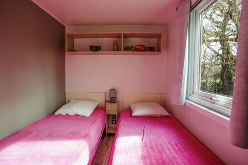 two beds in a pink room with a window at Au petit bonheur in Carnac