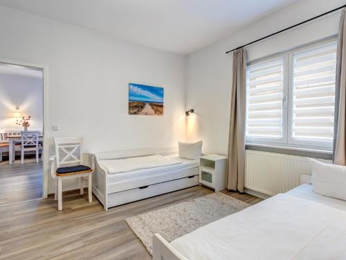 a white bedroom with two beds and a table at Haus Barnheide - Wohnung Sandburg in Bansin