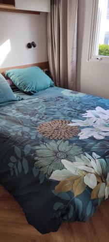 - un lit avec une couverture florale et une fenêtre dans l'établissement Mobile home 6 pers tout confort, à La Parée Preneau