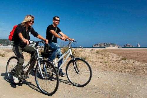 two people riding their bikes on the beach at Hotel Nereida in L'Estartit