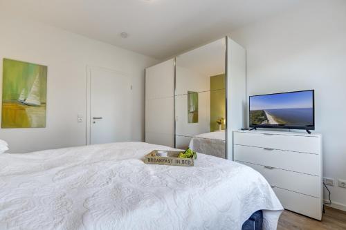 a white bedroom with a large bed and a tv at Haus Henny mit Sauna in Heringsdorf