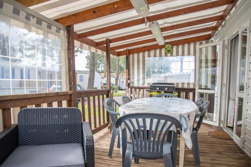 - une terrasse couverte avec une table, des chaises et un grill dans l'établissement Mobilhome tout équipé bois masson, à Saint-Jean-de-Monts