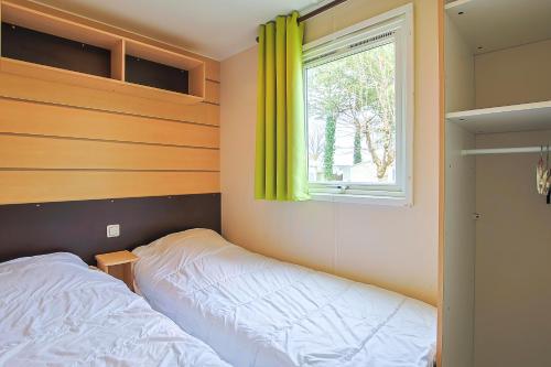 a bedroom with a bed and a window with yellow curtains at Mobilhome tout équipé bois masson in Saint-Jean-de-Monts
