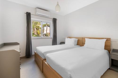 two beds in a room with a window at Vilar do Golf in Quinta do Lago