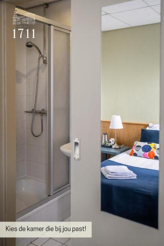 ein Badezimmer mit Dusche, einem Bett und einem Bett in der Unterkunft Hotel 1711 in Valkenburg