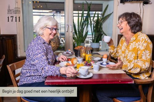 Dos mujeres mayores sentadas en una mesa comiendo comida en Hotel 1711, en Valkenburg