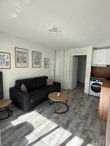 un salon avec un canapé noir et une table dans l'établissement Spacieux studio sur le port de hyeres, à Hyères