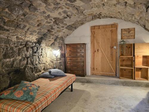 ein Schlafzimmer mit einer Steinmauer mit einem Bett und einer Holztür in der Unterkunft Maison Le Levant à Chauzon in Chauzon